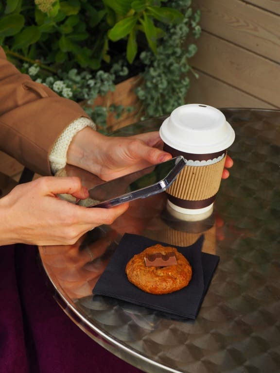 一人でスマホを見ながらコーヒーを飲む人のイメージ